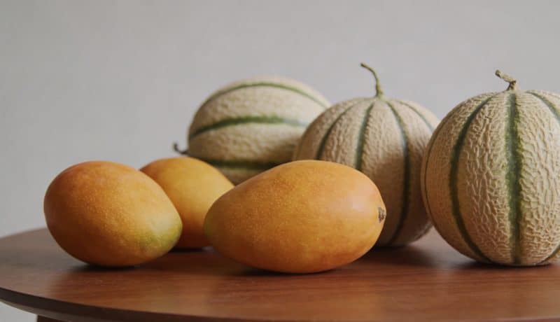 Assortiment de mangues et melons entiers sur table