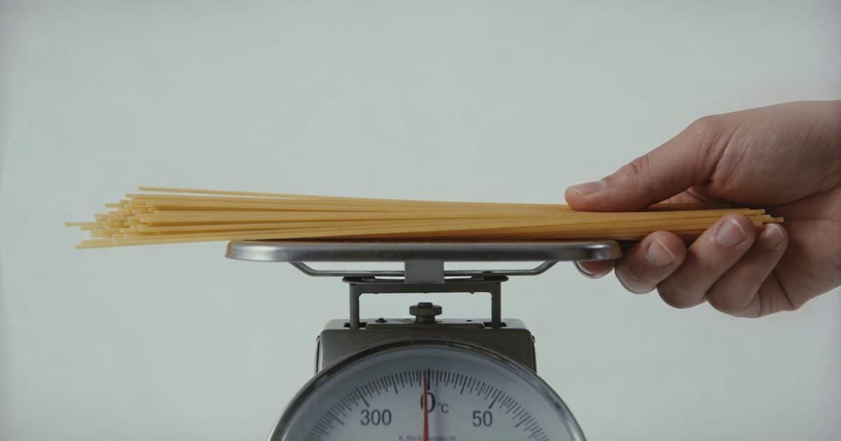 Main tenant une balance cuisine pesant portion spaghetti