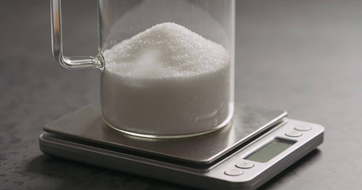 Verre doseur rempli de sucre blanc sur balance