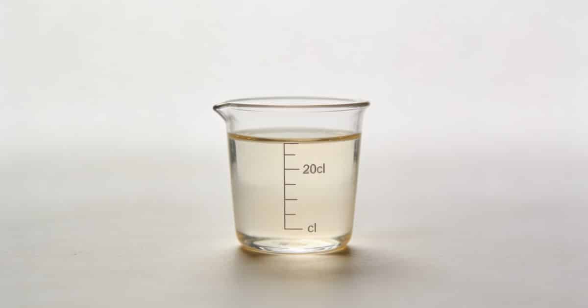 Verre doseur transparent rempli a 20 cl sur table